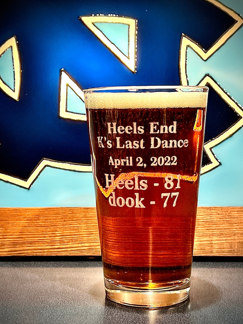 May include: A clear glass beer mug with a brown liquid inside. The mug is etched with the text "Heels End K's Last Dance April 2, 2022 Heels - 81 dook - 77".