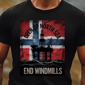 Puede incluir: Camiseta negra con un gráfico de la bandera noruega y una plataforma petrolera. El texto "OPEN UP NORTH SEA END WINDMILLS" está impreso en la camiseta.