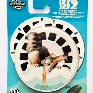 May include: A View-Master reel featuring Scrat the squirrel from the Ice Age movie franchise. The reel is blue and white with the title "Ice Age 2 The Meltdown" and a picture of Scrat holding an acorn.