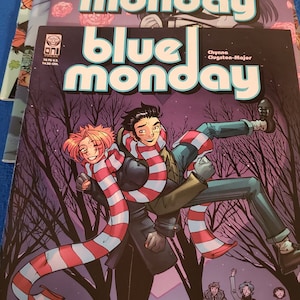 May include: A stack of comic books with a purple, pink, and blue color scheme. The cover of the top comic book features a man carrying a woman in his arms. They are both wearing striped scarves. The title of the comic book is "Blue Monday" with the text "Chynna Clugston-Major" below the title.