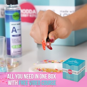 May include: A pink and white box with the text "I Love Crafting" on the front. The box contains a resin art kit with a variety of colorful embellishments, glitter, and resin.