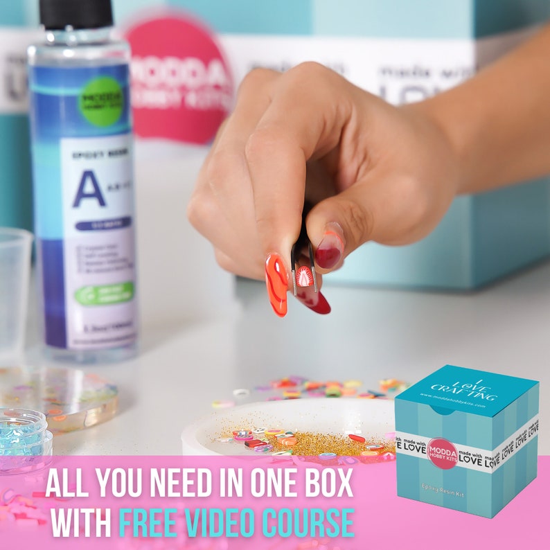 May include: A pink and white box with the text "I Love Crafting" on the front. The box contains a resin art kit with a variety of colorful embellishments, glitter, and resin.