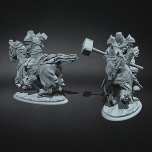 May include: A pair of grey, detailed miniature figurines of knights on horseback. One knight is holding a large hammer, while the other is holding a sword. Both knights are wearing armour and helmets.