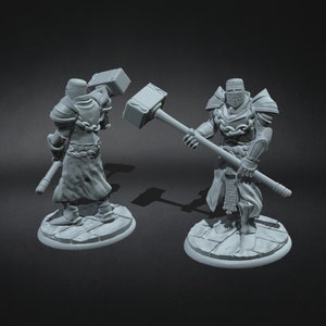 May include: Two grey painted miniature figures of knights wearing armour and holding a large hammer. The figures are standing on round bases.