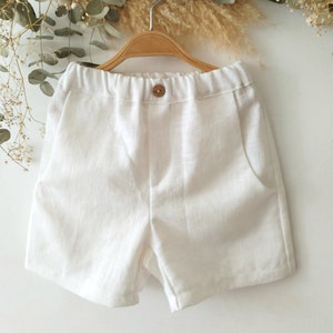 Puede incluir: Pantalones cortos de lino blanco con botón y cintura elástica.
