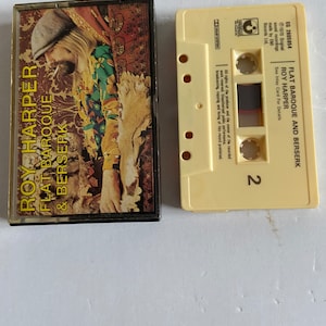 May include: A cassette tape with a yellow case and a brown and white label. The label has the text "Flat Baroque and Berserk" and "Roy Harper" on it. The cassette tape is a vintage item.