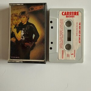 May include: A vintage cassette tape of "The Very Best of Dollar" album. The cassette case features a photo of a man and woman. The cassette tape is gray with the "Carrere Records" logo and album title printed on it.