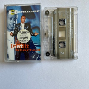 May include: A cassette tape of MC Hammer's debut album "Get It Started". The cassette tape is in a clear plastic case with a black label. The album cover features a photo of MC Hammer in a black leather jacket and a white shirt. The text "Get It Started" is printed in large, white letters on the album cover.
