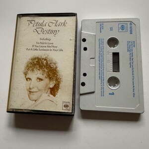 Peut inclure: Une tasse en céramique blanche avec une anse noire et le texte "But First, Coffee" en noir, dans une police manuscrite. La tasse est posée sur une surface blanche.