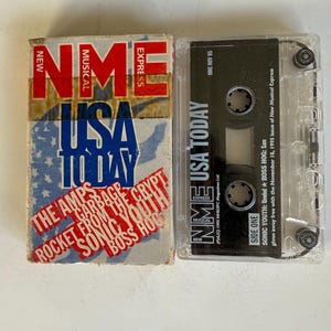 May include: A cassette tape with a white and red label that says "NME USA TODAY" and features the bands The Amps, Garbage, From The Crypt, Sonic Youth, and Boss Hog. The cassette tape is a free giveaway with the November 18, 1995 issue of New Musical Express.