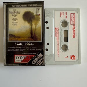 May include: A vintage audio cassette tape in a clear plastic case. The label features a landscape painting and the text "String Masterpieces." The case is labeled "Chrome Tape" and "Critics Choice."