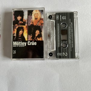 May include: A cassette tape of the album "Shout at the Devil" by the band Motley Crue. The cassette tape is in a clear plastic case with a black label. The label features the band's name and album title in white text. The cassette tape is a physical music format that was popular in the 1980s and 1990s.