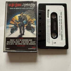 Könnte beinhalten: Eine Vintage-Kassette mit dem Titel "The Hit Squad Nightclubbing", die eine Disco-Compilation enthält. Das Cover zeigt eine futuristische Biker-Szene mit dem Text "Over 60 Minutes Non-Stop Disco!". Die Kassette ist schwarz.