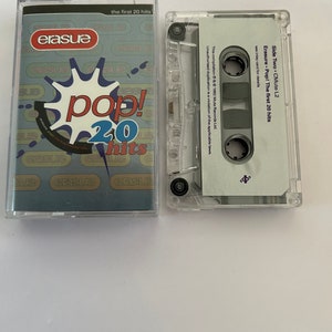 Puede incluir: Una caja de cassette de plástico transparente con una etiqueta blanca. La etiqueta tiene el texto "Erasure Pop! The first 20 hits" y "Side Two CMute L2".