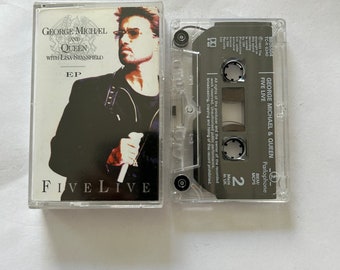 May include: A cassette tape with a clear plastic case. The tape is labeled "George Michael & Queen - Five Live" and features a photo of George Michael on the front. The tape is a 2-sided cassette with a black label on the back.