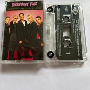 Peut inclure: Une cassette transparente avec l'album des Backstreet Boys "Quit Playing Games (With My Heart)". La pochette présente le groupe en costumes noirs. La cassette est visible à l'intérieur du boîtier.