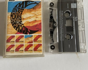 May include: A cassette tape with a black label that reads "felt ME AND A MONKEY ON THE MOON" and "side 1". The cassette tape is in a clear plastic case.