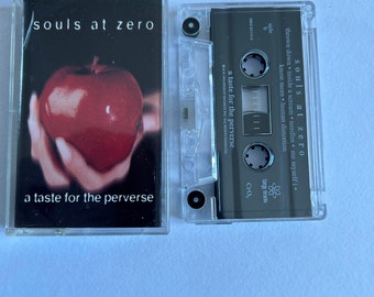 May include: A cassette tape with a red apple on the cover. The title of the album is "Souls at Zero" and the subtitle is "a taste for the perverse".