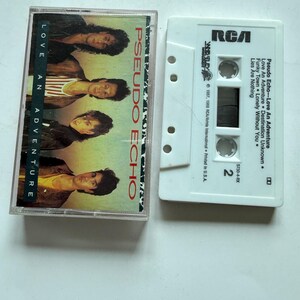 Può includere: Una musicassetta vintage di Pseudo Echo, intitolata "Love An Adventure". La copertina dell'album presenta una foto dei membri della band. La musicassetta bianca ha il logo RCA e i titoli delle canzoni stampati.