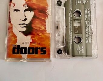 May include: A cassette tape of the soundtrack to the movie "The Doors", an Oliver Stone film. The cassette tape is clear plastic with a black label that says "The Doors" and "Oliver Stone Music from Original Motion Picture".