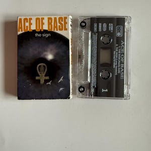 Può includere: Una musicassetta dell'album "The Sign" degli Ace of Base. La musicassetta è in una custodia di plastica trasparente con un'etichetta nera. L'etichetta riporta il nome del gruppo, il titolo dell'album e la lista delle tracce. La musicassetta è un formato musicale fisico che era popolare negli anni '80 e '90.