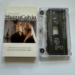 May include: A cassette tape and its case featuring Shawn Colvin with Mary Chapin Carpenter. The case has a photo of the artists and text that reads "one cool remove Shawn Colvin with Mary Chapin Carpenter". The cassette is clear.