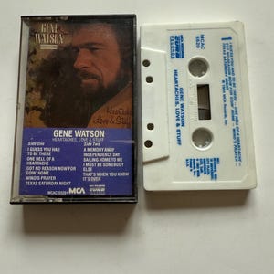 May include: A vintage cassette tape of Gene Watson's album "Heartaches, Love & Stuff." The cassette case is black with a portrait of Watson. The white cassette tape is next to the case, with the album title and track list visible.