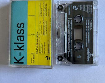 May include: A yellow and blue cassette tape with the title "K-klass" and the song "Rhythm is a mystery" by K-klass. The cassette tape is a Parlophone release with the catalogue number TCR 6302.