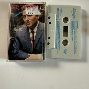 May include: A vintage audio cassette tape featuring Fritz Wunderlich's "Granada" album. The cassette case displays a portrait of the singer in a suit and tie. The tape is light gray with the label "Memoir".