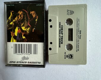 May include: A white cassette tape with the text "Cheap Trick at Budokan" and "Side Two" printed on it. The tape is labeled with the band's name, "Cheap Trick", and the album title, "Cheap Trick at Budokan".