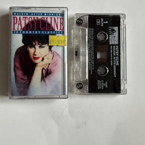 Puede incluir: Una cinta de casete del álbum "Walkin' After Midnight" de Patsy Cline. La cinta de casete está en una caja de plástico transparente con una etiqueta negra. La etiqueta tiene el título del álbum, el nombre del artista y el logotipo del sello discográfico. La cinta de casete es un álbum de 28 clásicos del country.