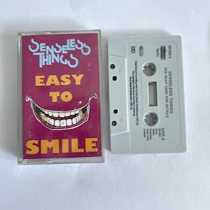 May include: A cassette tape with a purple and yellow cover featuring the band Senseless Things. The title of the album is "Easy to Smile".