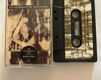 May include: A vintage cassette tape of The Psychedelic Furs' album "Book of Days." The cassette case features a sepia-toned image of the band members. The black cassette tape is next to the case, with the album title and CBS logo visible.