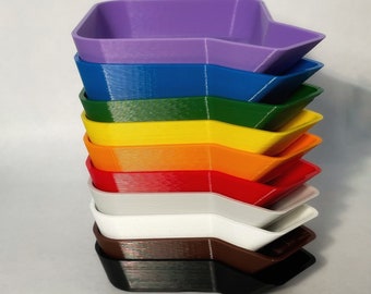 May include: A stack of eight colorful plastic trays, each with a slightly different shape. The trays are arranged in a rainbow order, starting with purple and ending with black.