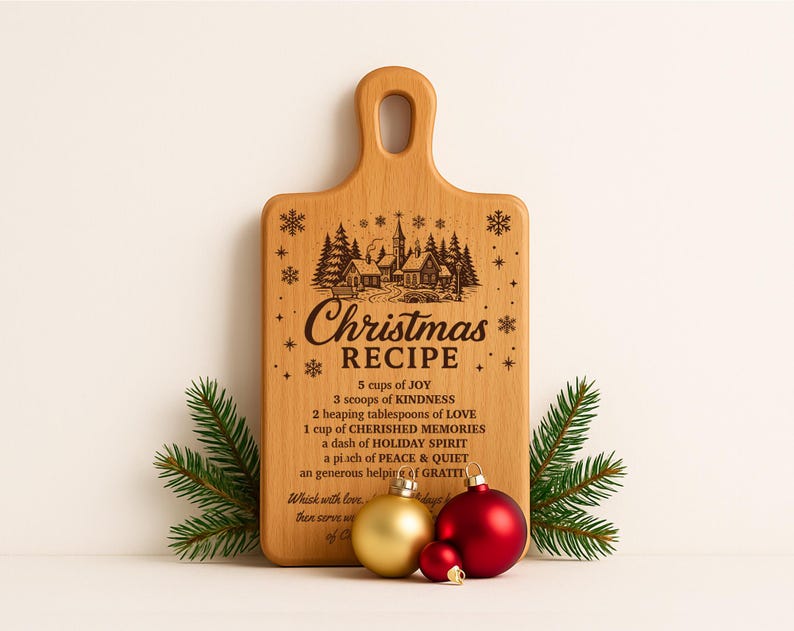 May include: A wooden cutting board with a handle, engraved with a Christmas recipe and a winter village scene. The board is decorated with pine sprigs and gold and red Christmas ornaments.