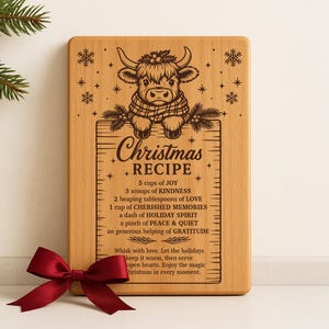 May include: A rectangular wooden cutting board with a carved design and text. The design features a cow wearing a scarf above the words "Christmas Recipe." The recipe includes ingredients like joy and kindness. A red bow is at the bottom.