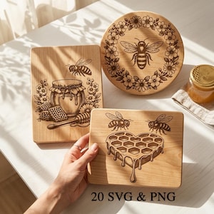 May include: Wooden cutting boards with bee and honeycomb designs. One board features a bee and floral wreath, another has a honey jar and honeycomb, and the third has a heart-shaped honeycomb with bees. A jar of honey is also present.