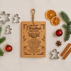 May include: A wooden Christmas recipe cutting board with a rope handle, surrounded by festive decorations. Includes cookie cutters, ornaments, pine sprigs, dried orange slices, and cinnamon sticks. The board features engraved text with a holiday recipe.
