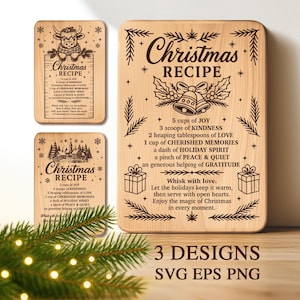 Puede incluir: Tres tablas de recetas navideñas de madera con diseños grabados. Una presenta una vaca, otra una escena invernal, y la más grande tiene campanas y texto. Las tablas incluyen una receta con ingredientes como alegría y amabilidad.