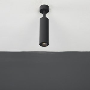 May include: A black cylindrical ceiling light fixture with a white light shining down.
