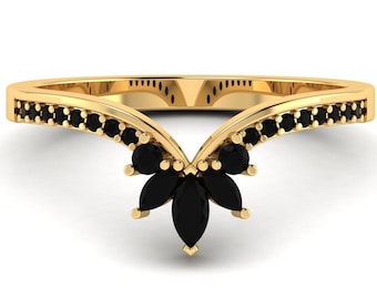 May include: A gold ring with a V-shaped band and black gemstones. The band is set with small black stones and the center features a cluster of larger black stones.