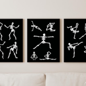 Puede incluir: Tres impresiones artísticas enmarcadas con ilustraciones de esqueletos blancos sobre fondo negro. Cada impresión muestra diferentes poses de esqueleto, incluyendo posiciones de baile y yoga. La obra de arte se exhibe sobre un sofá blanco.