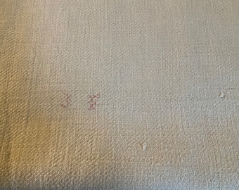 May include: Close-up of a light beige fabric with a subtle woven texture. There are two small red marks on the fabric.