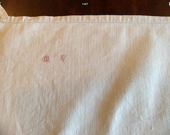 May include: A white linen tea towel with red embroidered letters "M" and "T" in the center.