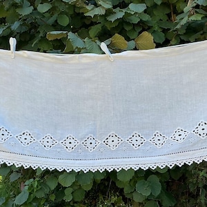 May include: A rectangular white fabric valance featuring intricate cutwork embroidery in a repeating diamond pattern along the bottom and side edges, finished with a delicate scalloped crochet lace trim along the entire lower border.