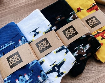 May include: Four pairs of socks with a plane pattern. The socks are in blue, white, black, and yellow. Each pair has a brown tag with the words "Top Dog" printed on it.