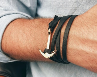 May include: A black leather wrap bracelet with a gold anchor charm.