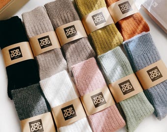May include: A collection of ten pairs of ribbed socks in various colours including black, grey, beige, brown, olive green, orange, white, pink, sage green, and blue. Each pair is secured with a tan paper band featuring the text TOP DOG LONDON.