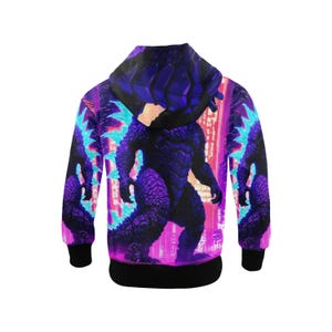 Op de afbeelding: Een zwart hoodie met een paarse en blauwe Godzilla-grafische print. De print toont Godzilla die in een stad staat met neonlichten.