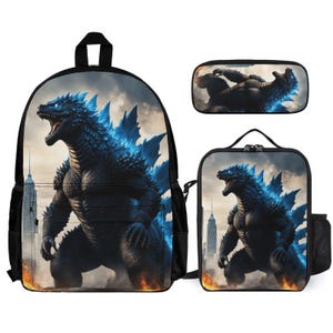 May include: A black backpack, lunch bag, and pencil case set featuring a blue and gray Godzilla monster graphic. The backpack has a large main compartment and a front pocket. The lunch bag has a zipper closure and a handle. The pencil case has a zipper closure.